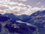 Panoramic view from above a winding mountain lake, forests, and peaks in Glacier National Park; ideal for an RV rental.
