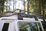 Close-up: Rhino-Rack roof rack on a white RV rental, ideal for forest camping trips and gear transport.