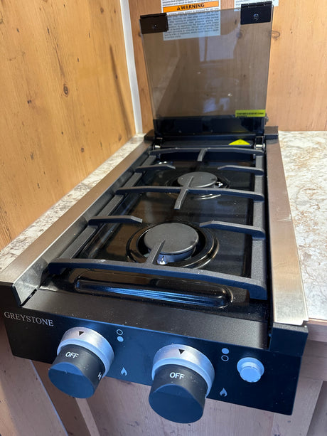 This RV rental kitchen features a clean Greystone two-burner cooktop, ready for your adventures.