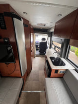 Inside an rv rental: galley kitchen, TV, seating, and a clear view into the cockpit.