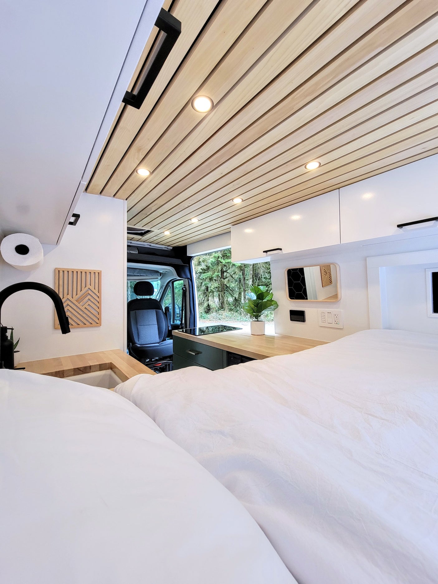 Cozy RV rental interior with a modern kitchen, wooden ceiling, and comfortable bed. Enjoy nature on your mobile adventure!