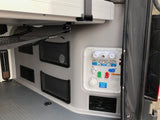 Essential water system panel with hookups and outdoor shower in an RV rental's cargo area, with mesh storage.