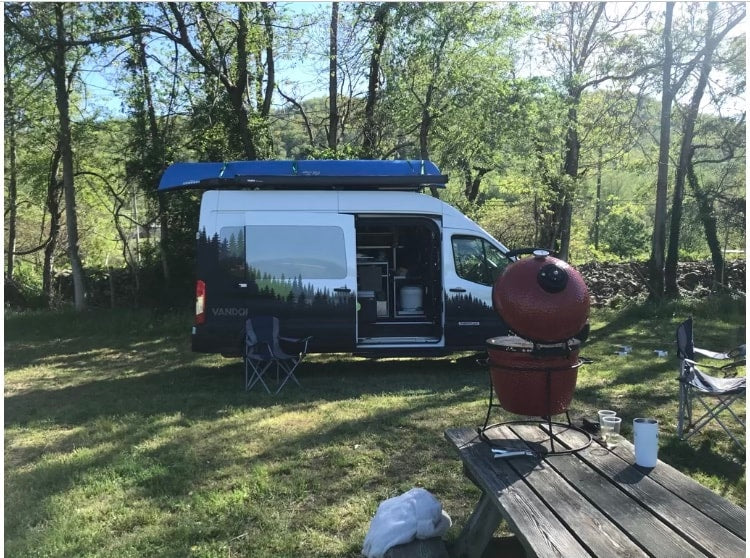 RV rental camper van, featuring a canoe & a Kamado grill on a picnic table, set in a peaceful wooded campsite. — photo 3