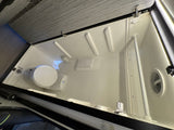 An RV rental compact wet bath with toilet, shower, drain, and molded interior walls for efficient travel.