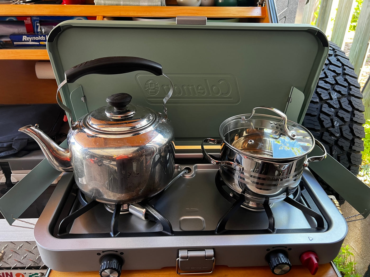 This RV rental cooking setup features a portable stove with a shiny kettle and a pot, ready for outdoor meals. — photo 17