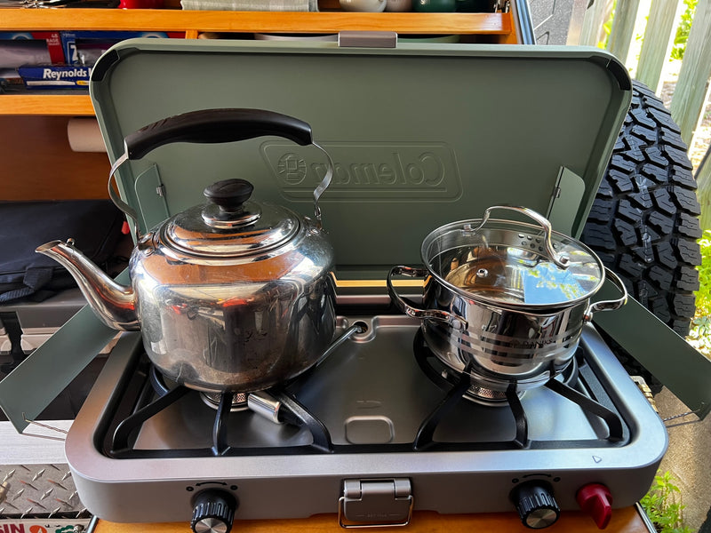This RV rental cooking setup features a portable stove with a shiny kettle and a pot, ready for outdoor meals. — photo 17