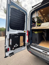 Inside an RV rental: a customized camper van with an outdoor water heater, cozy bed, and storage solutions.