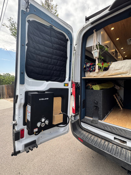 Inside an RV rental: a customized camper van with an outdoor water heater, cozy bed, and storage solutions.