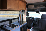 This RV rental features a camper van interior with a kitchenette, wooden overhead cabinets, and a view into the driver's cabin.