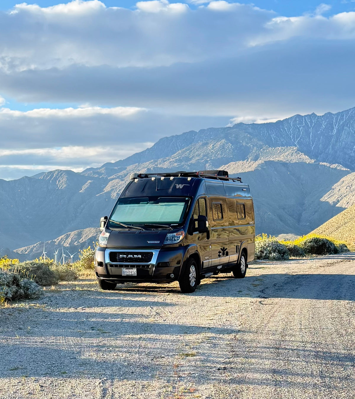 Scenic rv rental adventure: A black camper van is parked on a dirt road