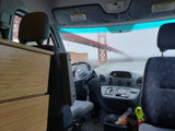 Inside an RV rental, a stunning view of the Golden Gate Bridge emerges from the fog over the bay, as seen from the driver's seat.