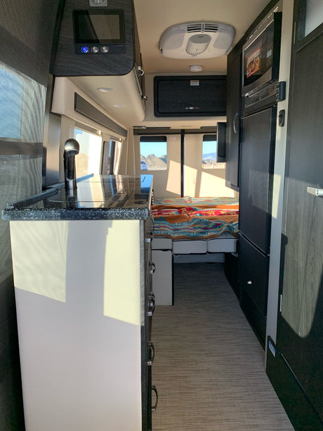 Step inside this modern RV rental! Features a compact kitchen, comfortable bed area, and onboard amenities for your adventure.