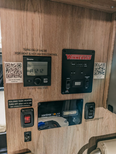 RV rental control panel: View of Truma heating, Winnebago systems, and Xantrex solar charger, managing heat, water, and power.