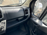 Inside an RV rental: passenger dashboard with vents, storage, and door controls. A dusty windshield shows the exterior.