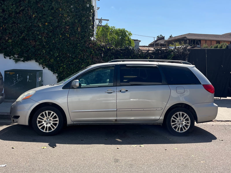 A silver minivan parked on a sunny street near an ivy-covered wall. Consider this vehicle as an alternative to an rv rental.|Rear view of a silver minivan with open tailgate — photo 1