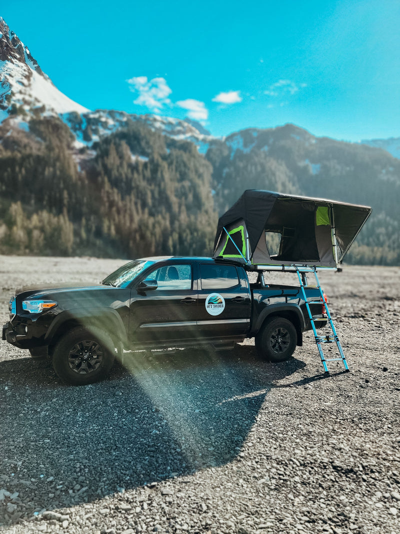 Black pickup truck with open rooftop tent & ladder on gravel, mountains in background. Perfect **RV rental** for adventure. — photo 9