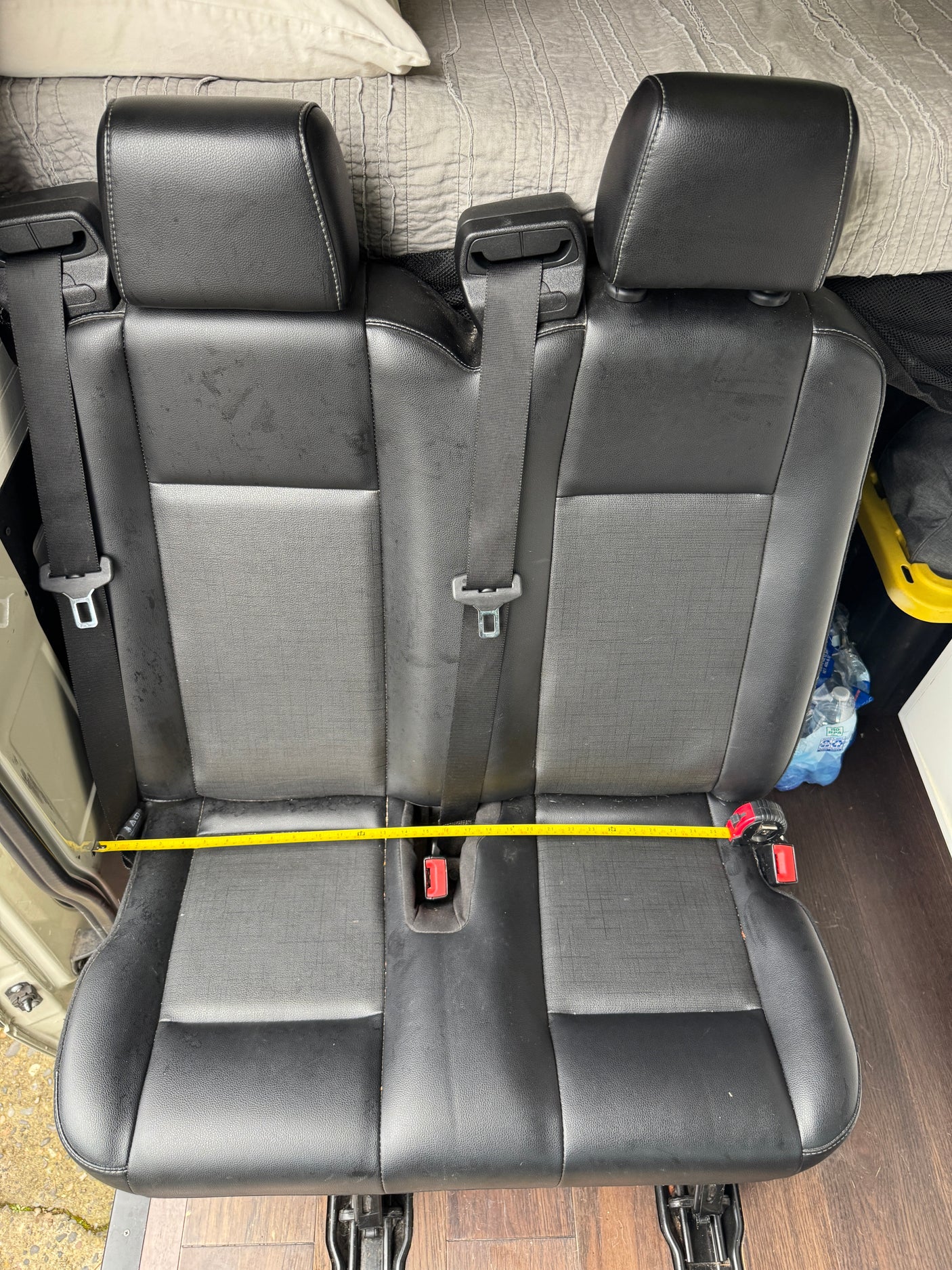 RV rental: Black two-person bench seat, ~29 inches wide with seatbelts, shown in a vehicle interior.