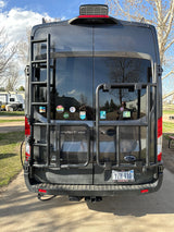 Dark grey Ford Transit RV rental van with a ladder and rear carrier, ideal for adventurers and travel.