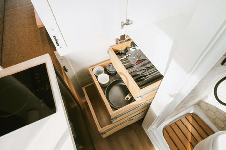 RV rental interior: compact kitchen with drawers, induction cooktop, shower, & seating.