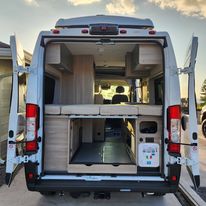  and storage space in a compact camper van.|RV rental interior with comfy seating — photo 8