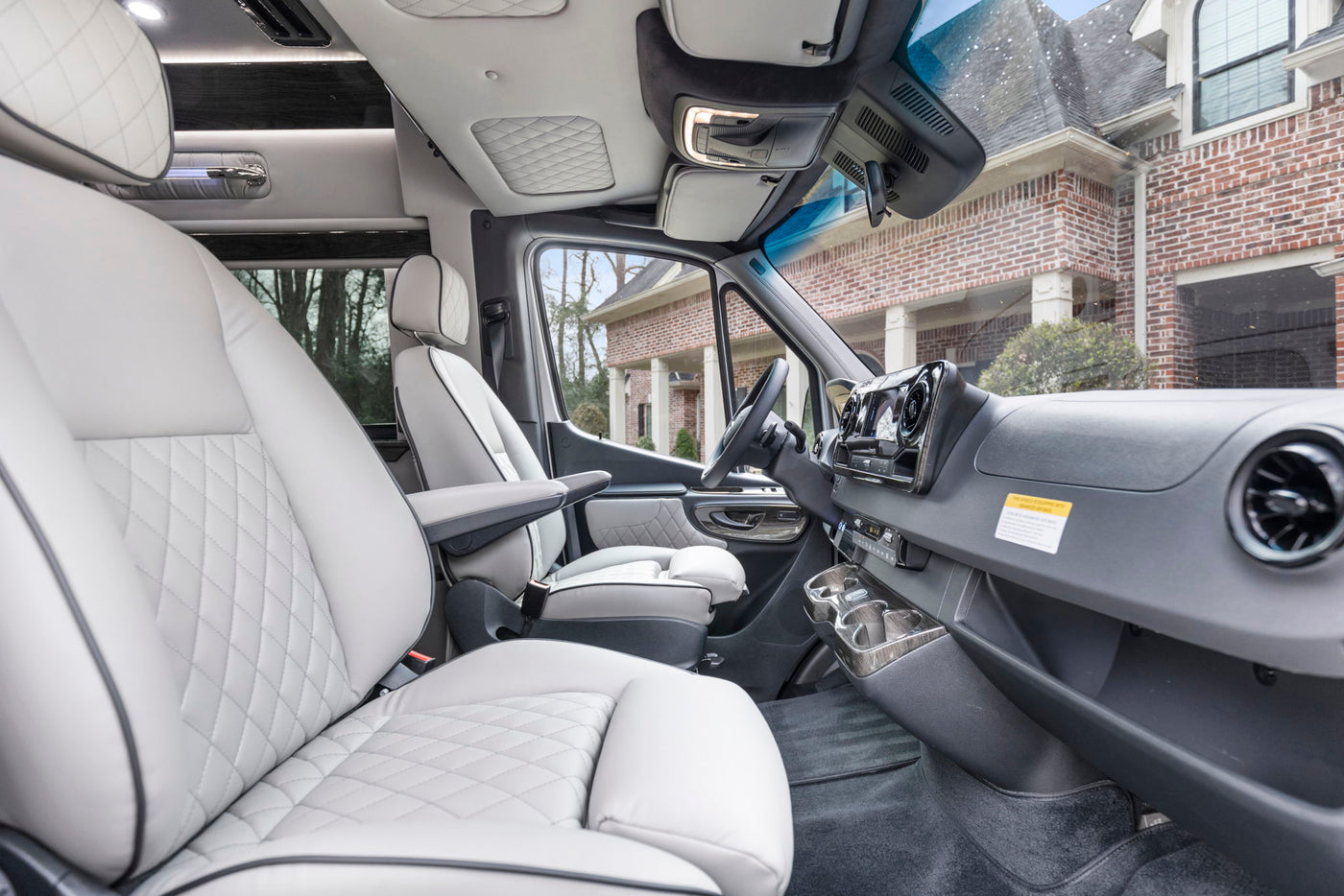  and modern amenities.|Plush grey captain's chairs with footrests in a luxurious RV rental van's interior — photo 15