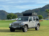Silver Jeep Wrangler with rooftop tent, ideal for an RV rental adventure amidst Kauai's mountains.