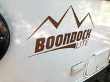 Side of a white RV featuring a brown "BOONDOCK LITE" mountain decal, ideal for an RV rental adventure.