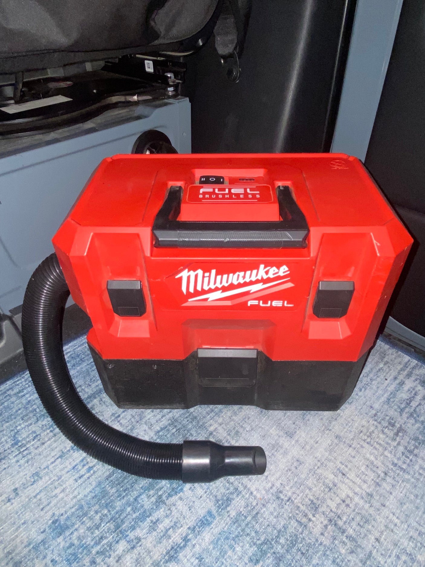 Red Milwaukee FUEL cordless vacuum with hose & nozzle, perfect for keeping your RV rental clean.