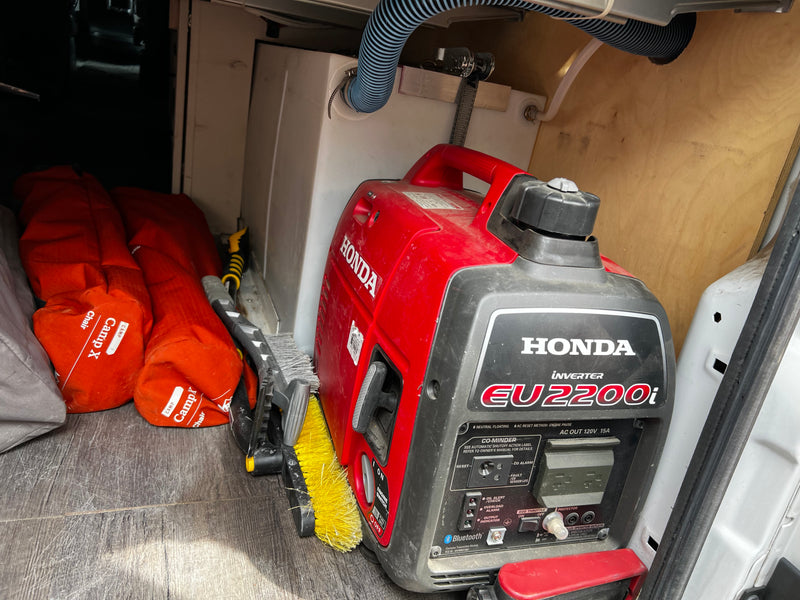 Essential gear in an RV rental: Honda inverter generator, CampX chairs, and cleaning brush stored in the cargo area. — photo 13