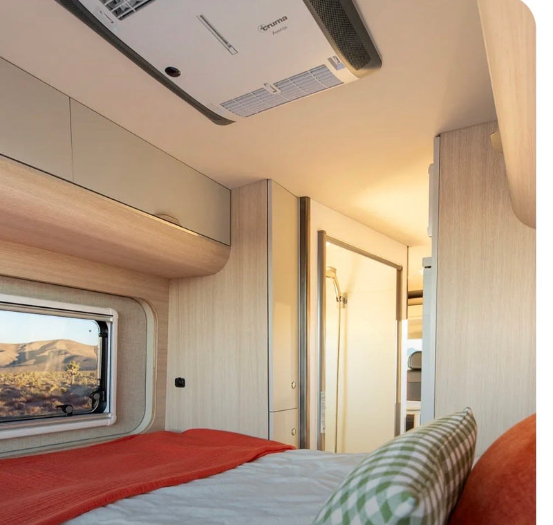 RV rental's cozy bedroom features a bed, desert window view, overhead AC, and a compact shower stall. Perfect for travel. — photo 4
