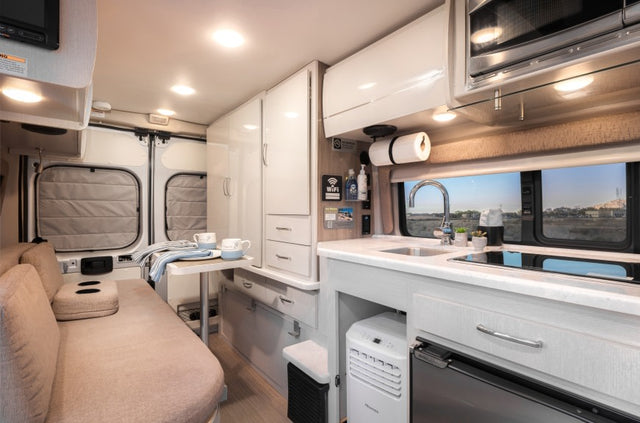  and the open road ahead through the windshield.|Bright rv rental interior with a dining table