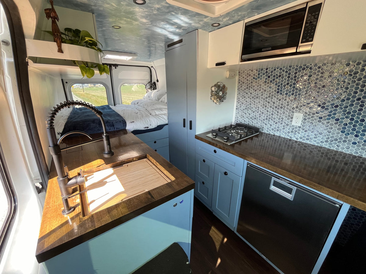 Spacious rv rental kitchen & bedroom area with blue cabinets — photo 1