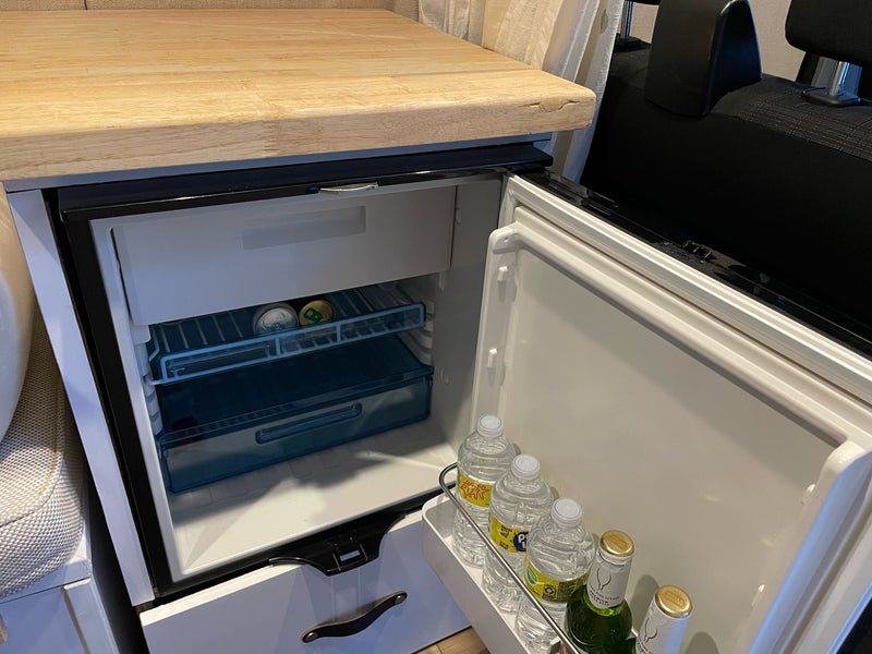 This RV rental features a well-stocked mini-fridge with drinks, a small freezer, and a wooden counter, ready for your travels. — photo 14