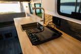 RV rental kitchenette featuring a sleek induction cooktop, sink, and bright wood countertop.