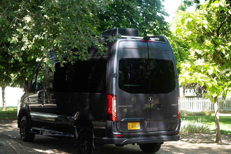Luxury Mercedes Sprinter camper van, an excellent RV rental choice, parked outdoors under a canopy of green trees. — photo 17