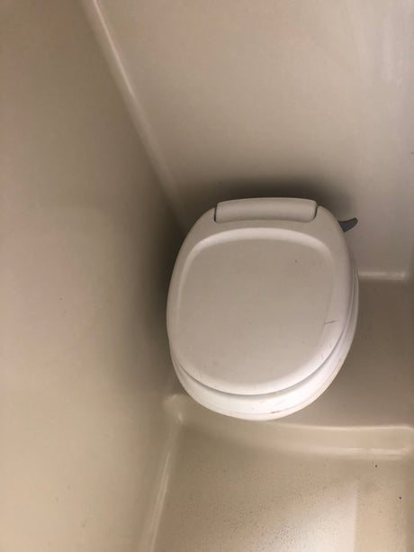 A clean, compact toilet inside an RV rental bathroom, ready for your road trip comfort and convenience.