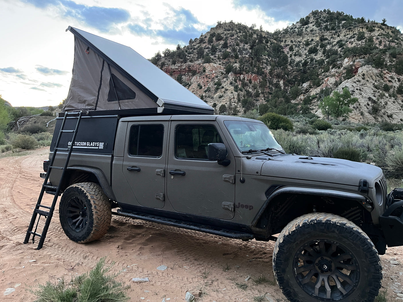 Grey Jeep Gladiator with a pop-up rooftop tent, an ultimate rv rental for off-road camping & adventure in the mountains.