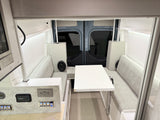 Enjoy comfortable meals in this RV rental's camper van dinette, featuring benches, a table, and a convenient control panel.