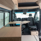 RV rental's modern camper van interior: sleek kitchen with induction cooktop, swiveling front seats, and pull-out table.