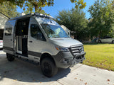 Custom Mercedes-Benz Sprinter Winnebago camper van with open side door, ideal for RV rental, parked on a driveway.