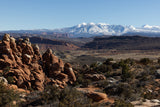 Vast desert landscape: red rock formations and distant snow-capped mountains. Ideal for an RV rental adventure!