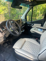 Step into this luxurious rv rental: a modern Mercedes-Benz driver's cabin featuring spacious light quilted leather seats and sleek dashboard.