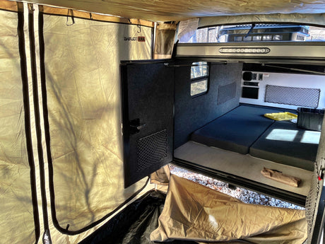 Spacious RV rental teardrop camper interior with bed & attached tent for camping comfort & outdoor living.