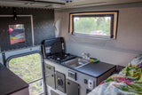 Explore this RV rental's compact interior: kitchen with sink/stove, comfy bed, and window views for on-the-go adventures.