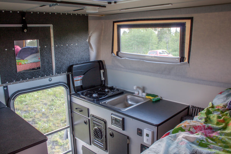 Explore this RV rental's compact interior: kitchen with sink/stove, comfy bed, and window views for on-the-go adventures. — photo 7