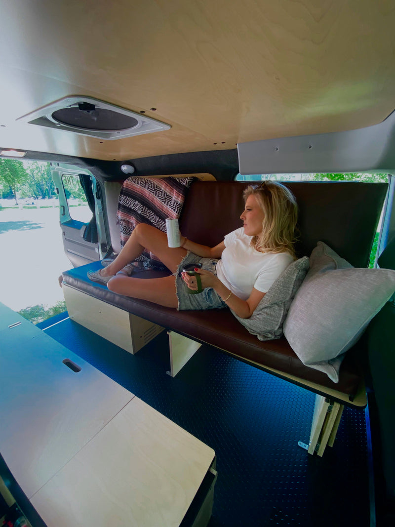 Woman relaxes inside a spacious RV rental, showcasing the comfy camper van interior with an inviting outdoor view. — photo 2