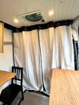 Clean RV rental interior: white paneled ceiling with fan & lights, dividing privacy curtains, and bamboo tables.