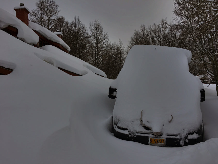 Deep snow buries a car and house roof. This extreme winter scene highlights the need for careful RV rental planning.