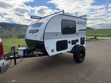 Ready for adventure! This Sunray Sport travel trailer, ideal for rv rental, is parked lakeside with a scenic view.