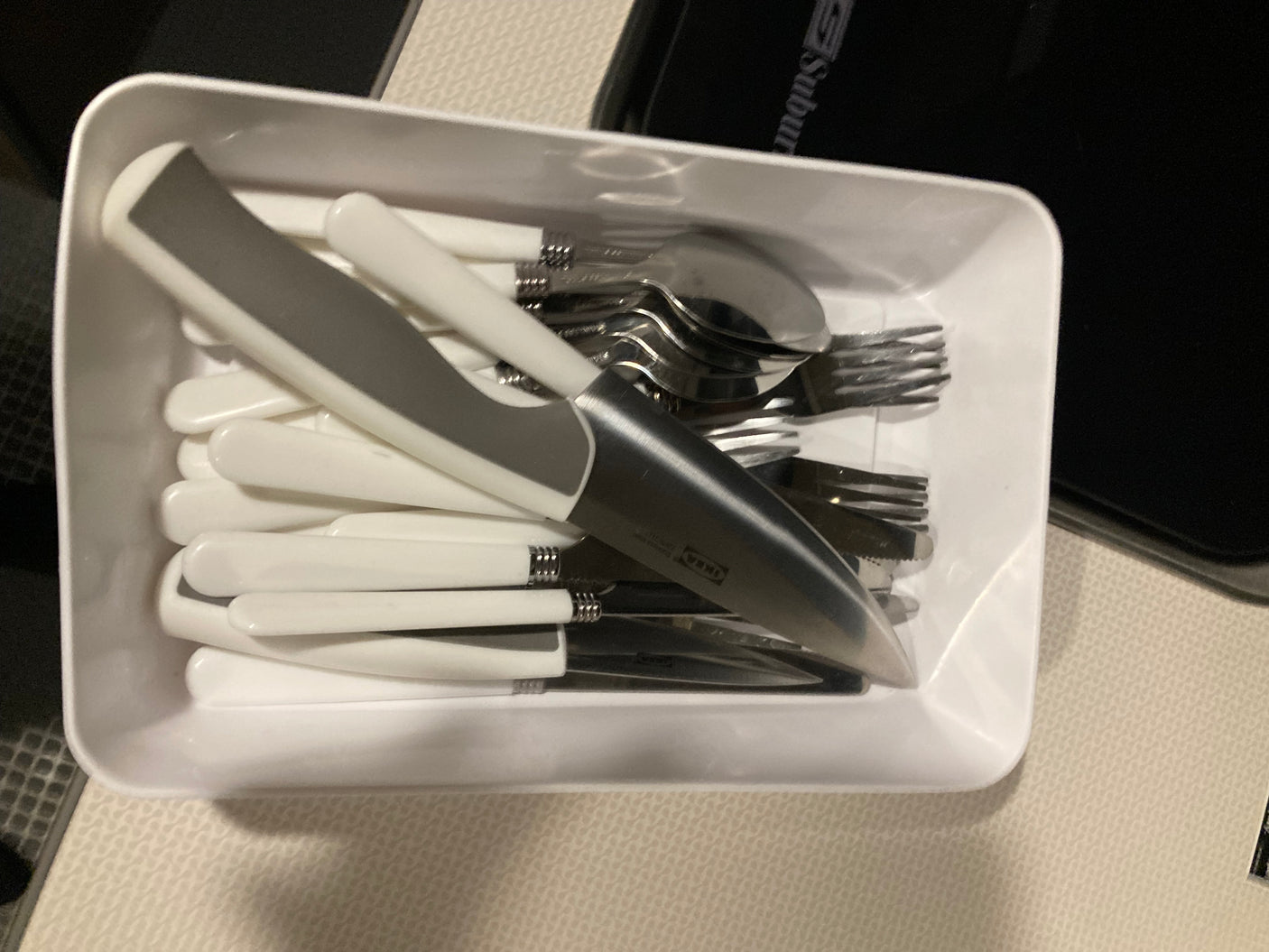 A white tray holds an organized set of cutlery (knives, forks, spoons), practical for your RV rental kitchen.